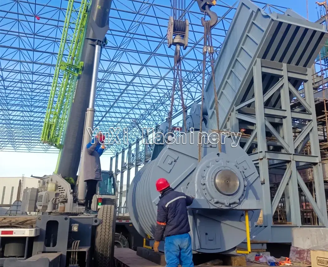 Heavy-duty industrial shredder or rotary machine being lifted by a crane during installation at a facility.
